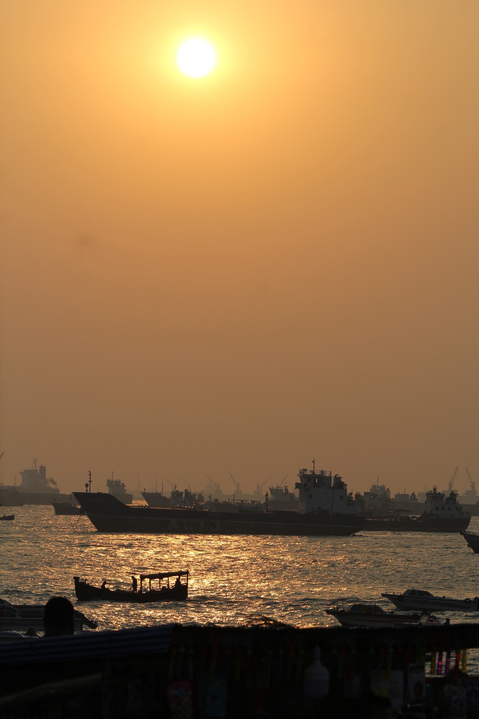 Ships and small boats on gold water at dusk